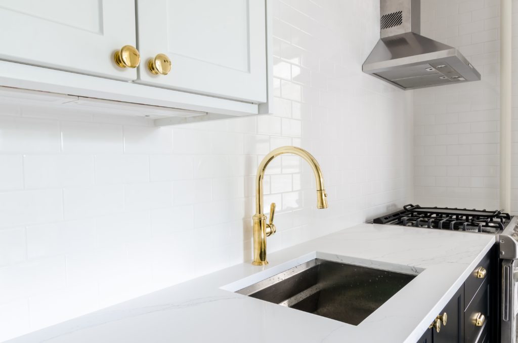 Modern Minimalist Kitchen Design with Brass Faucet and Cupboard Handles