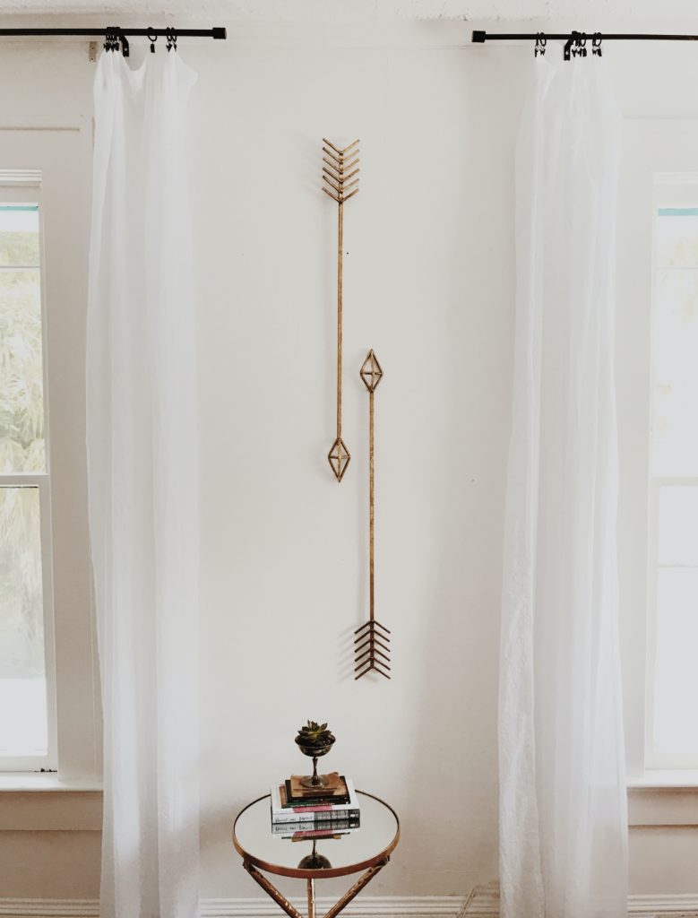 Boho home styling with wooden decorative arrow artwork and light and airy curtains