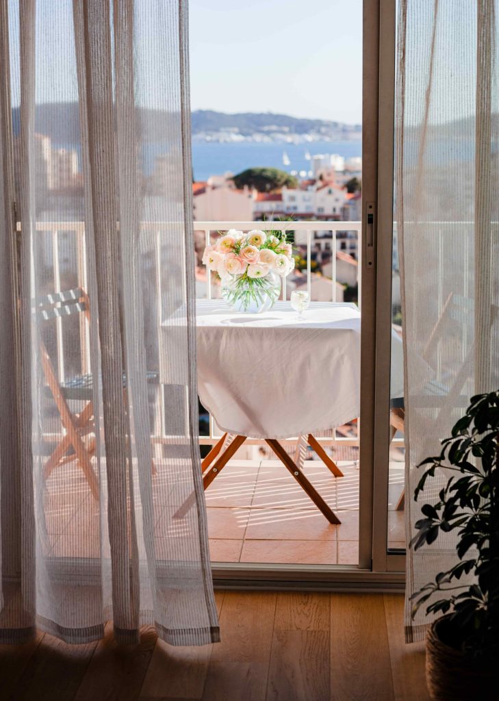 Image of a balcony with a sea view and table set for two from a blog post "Interior Design Tips for Airbnbs" by online interior designer Chelsey Home